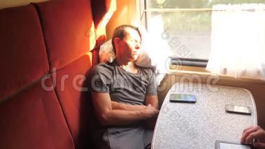 坐在客车里坐火车的人睡觉。 慢动作视频。 男人睡在火车上